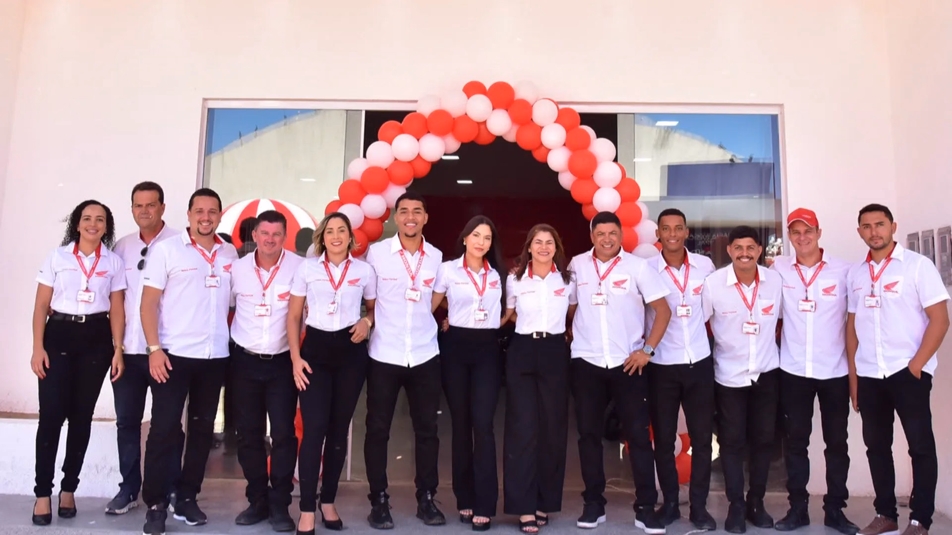 Equipe da Motos Pombal reunida em frente à loja, com arco de balões na entrada - 1 de 7