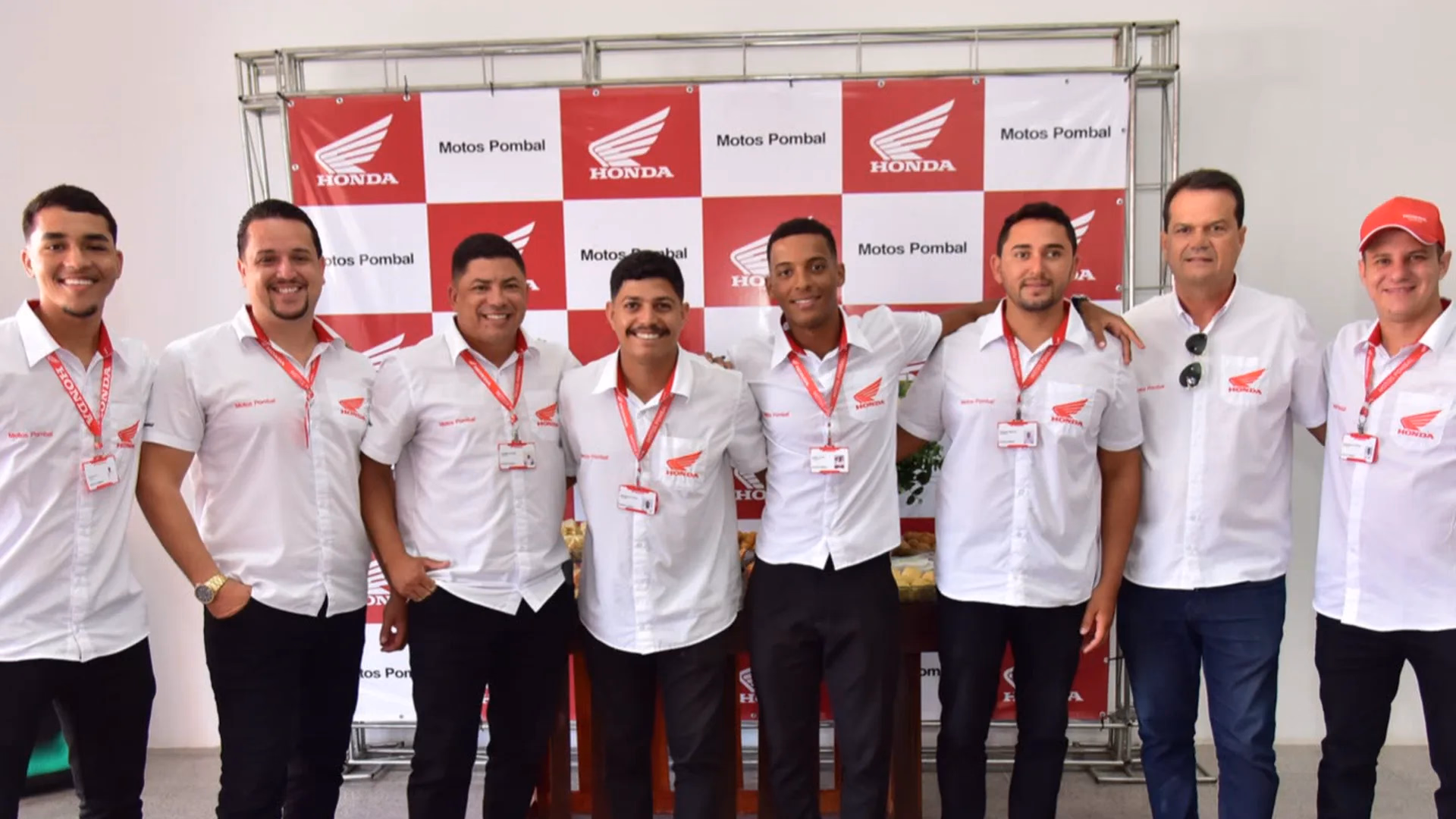 Equipe de vendas da Motos Pombal diante do painel Honda e Motos Pombal - 5 de 7