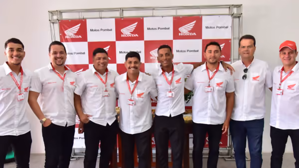 Equipe de vendas da Motos Pombal diante do painel Honda e Motos Pombal